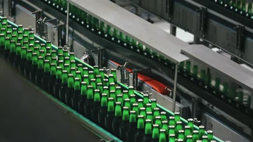 Green glass beer bottles moving on industrial conveyor belt