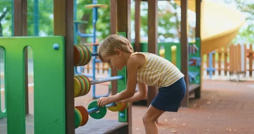 Niño jugando con un ábaco en el patio de recreo en un día soleado