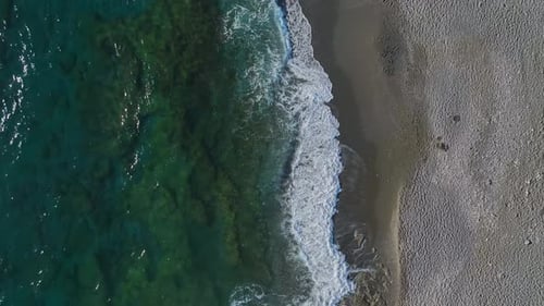 Aerial Video of a Golden Sand Beach With Textured Ripples and Clear Blue Waves Glistening Under the