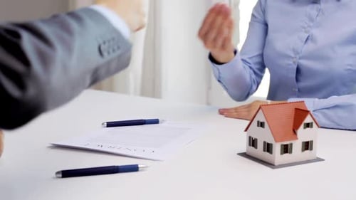 Businessman hands house keys to woman in office real estate deal