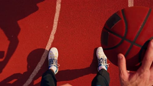 Close-up of a basketball guy's shadow on the floor of a basketball court while dribbling the ball