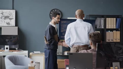 Indischer Programmierer diskutiert Code mit einem Kollegen aus dem Nahen Osten im Amt