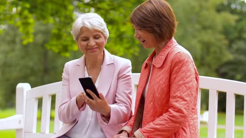 Smiling women with phone on park bench