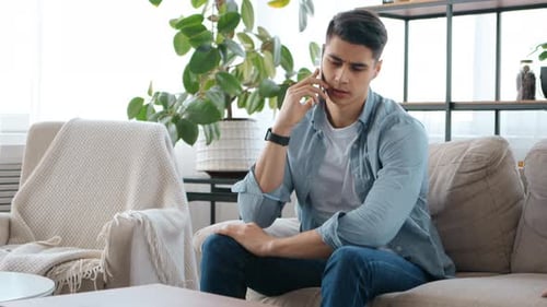 Worried Man Talking on Phone Inside