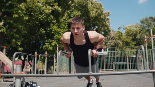 Muscular Man Doing Dips in Urban Park