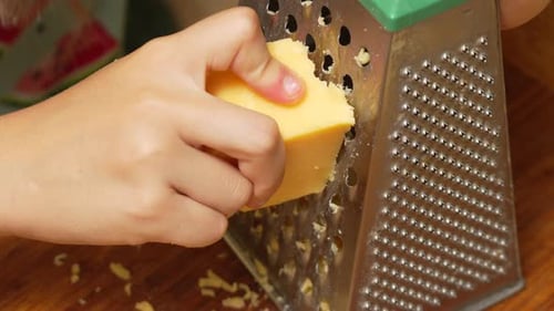 Nahaufnahme einer Hand, die Käse reibt