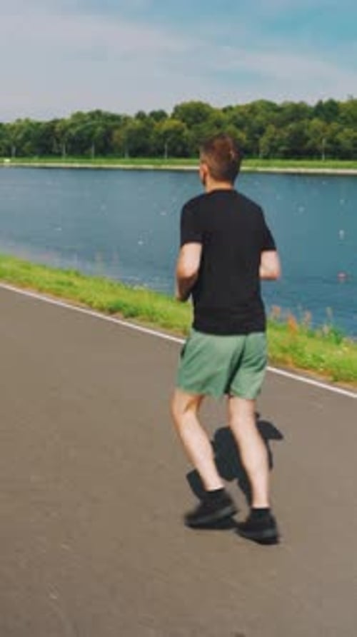 On a Beautiful Sunny Morning a Young Man Jogs Energetically By the River Reveling in the Vibrant