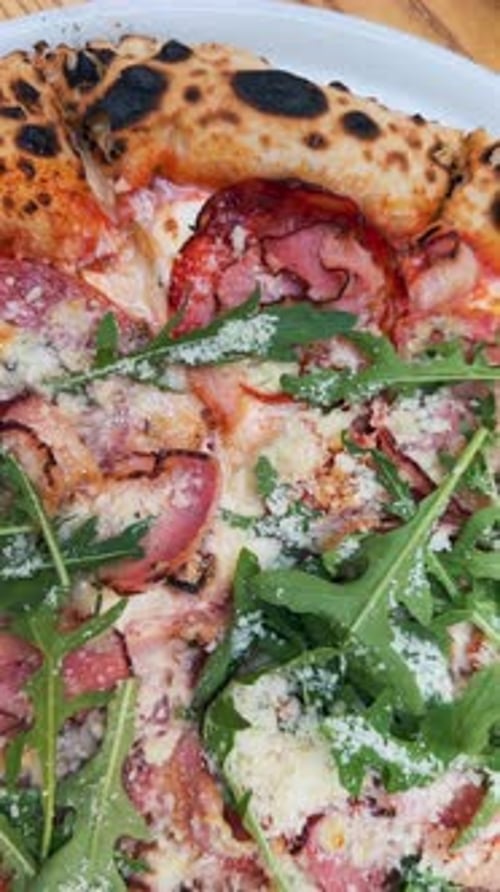 A Detailed Photo Capturing the Deliciousness of a Pizza on a Table Out on the Terrace