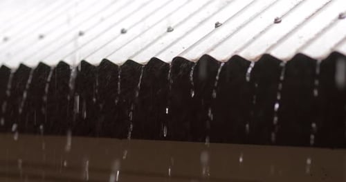 Rain pouring off corrugated tin roof during thunderstorm