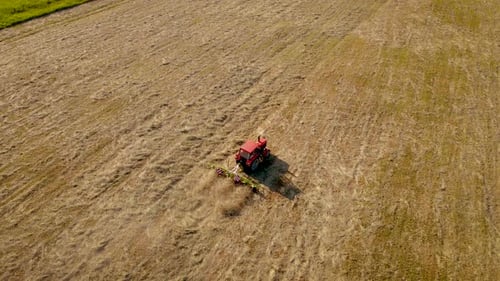 Trator com Hay Tedder aerando e acelerando a secagem da palha em campo agrícola para embalá-la