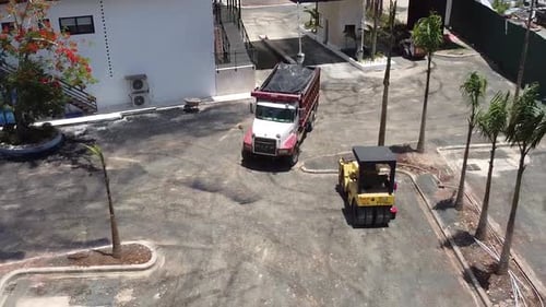 Luftaufnahme von schweren Maschinen, LKW bringt Material für die Asphaltierung eines Gewerbeparkplatzes, schwer m
