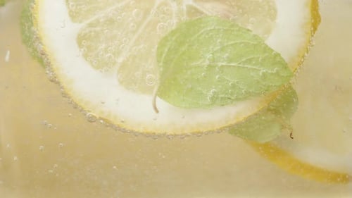 I stir the Lemonade with a spoon. Slices of Lemon and Mint are spinning inside. close-up, slow motio