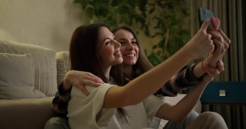 Two Smiling Friends Taking a Selfie Indoors