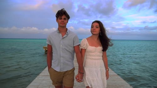 Romantic couple walks on pier. Turquoise tropical ocean water at sunset. Honeymoon destination