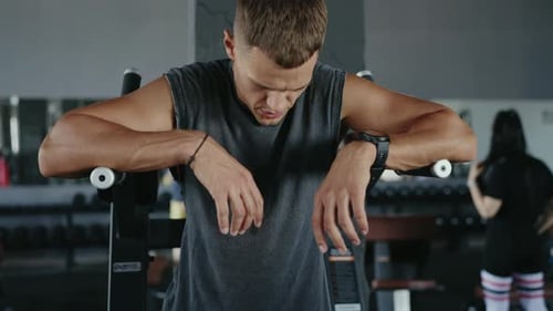 Focused Man Resting Between Workouts at the Gym in Fitness Center