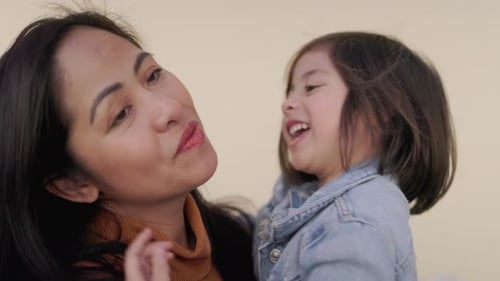 Affectionate Mother Kisses Smiling Child in Close Up