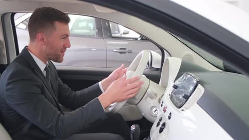 Young Man Smiles in New Car at Dealership