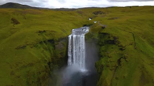 cinematic drone footage of Skógafoss Waterfall in Iceland, capturing the immense curtain of water