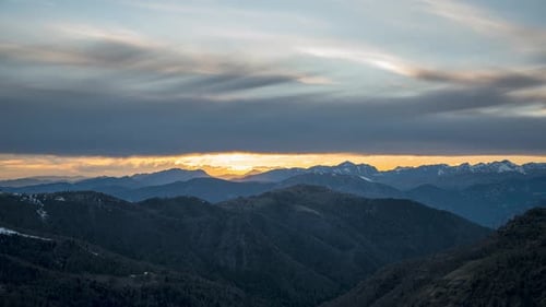 Sunset over mountainous landscape with dramatic clouds and soft light, scenic view