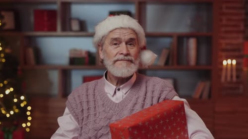 Senior Man Holding Gift Wearing Santa Hat