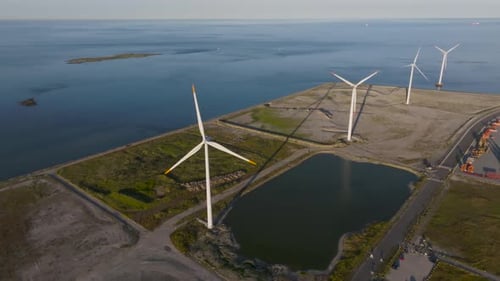 An aerial view a source of clean energy, four wind turbines in a row and rotating blades on a summer