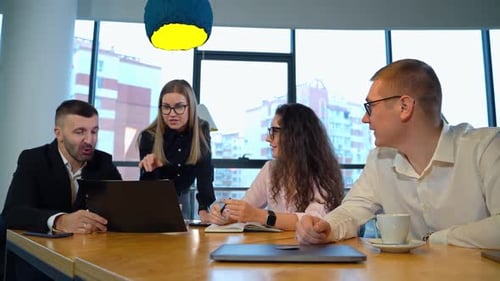 Business team sitting at table under two blue-and-yellow lamps. Office people having meeting