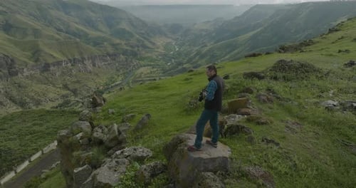 Landscape Photographer With Camera Standing On The Rock Taking Pictures Of Mountain Range And Valley