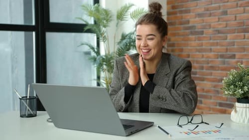 Successful Woman Celebrates at Desk Using Laptop