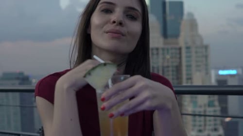 Happy pretty woman smiling enjoying cocktail on rooftop terrace bar in the city