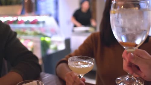 People toasting with cocktails at a bar