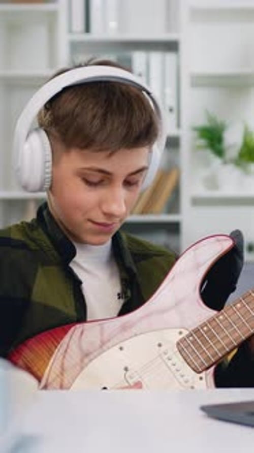 Teen Plays Electric Guitar at Desk at Home