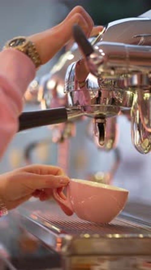 Woman Making Espresso at a Shiny Coffee Machine