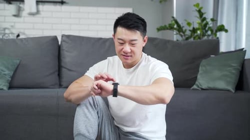 sporty man using fitness smart watch at home. Young male watching a smartwatch training data app