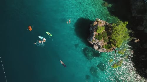 Stunning aerial view of sea with people have fun and swimming in clear waters near rocky coastline i
