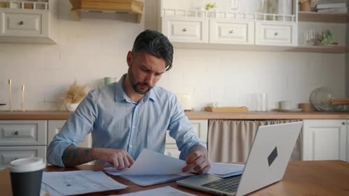 Adult Man Reviewing Documents in Kitchen