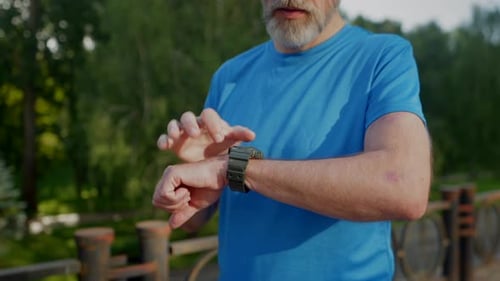 Man Checks Smartwatch in Park Setting