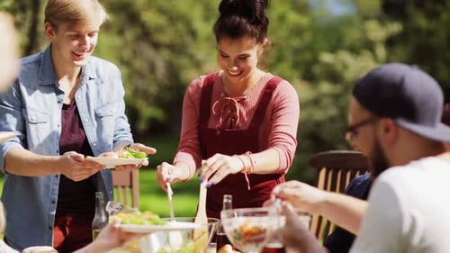 Leisure, Holidays, Eating, People And Food Concept - Happy Friends Having Dinner At Summer Garden...