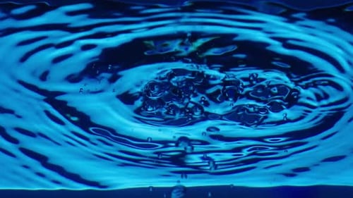 Bottom View of Water Surface with Drops Dripping and Forming Waves and Ripples