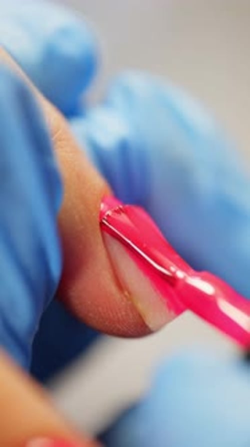 Applying vibrant pink nail polish with brush close up