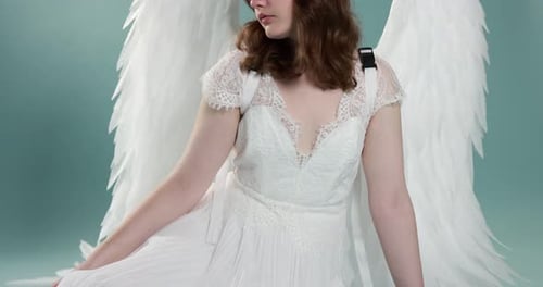 Belle fille avec des ailes d'ange sur fond bleu clair, caméra se déplaçant vers le haut