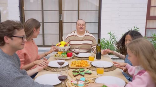 Family Holding Hands in Prayer Before Meal