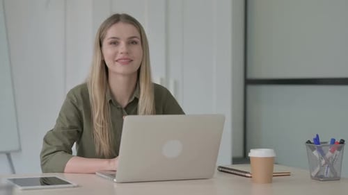 Young Woman Smiling at Laptop in Office