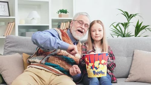 Grandfather and Granddaughter Sharing Popcorn at Home