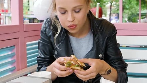 Woman Eating Sandwich at an Outdoor Cafe