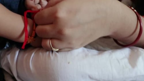 Tying a Red String Bracelet on a Child
