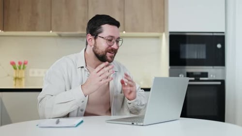 Emotional Man Conducting Distance Meeting on Personal Laptop at Home Office