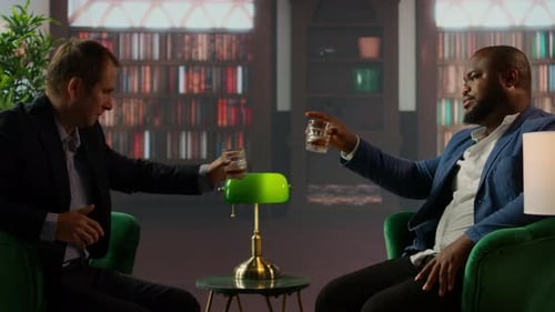 Men Sitting in Armchairs Chatting Over Drinks