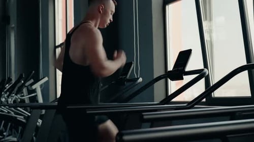 Muscular Man Runs on Treadmill at the Gym