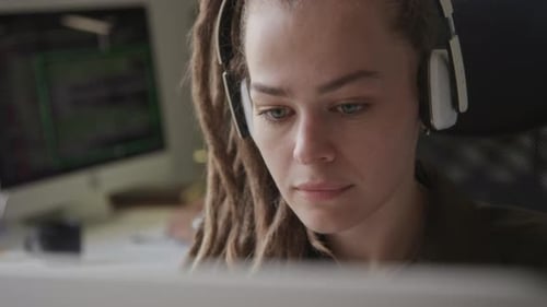 Junge Frau mit Kopfhörern programmiert Programmieren im Büro