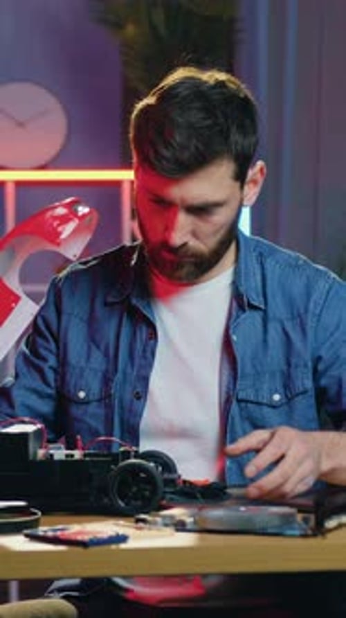 Man Assembling Small Red Car at Table Indoors